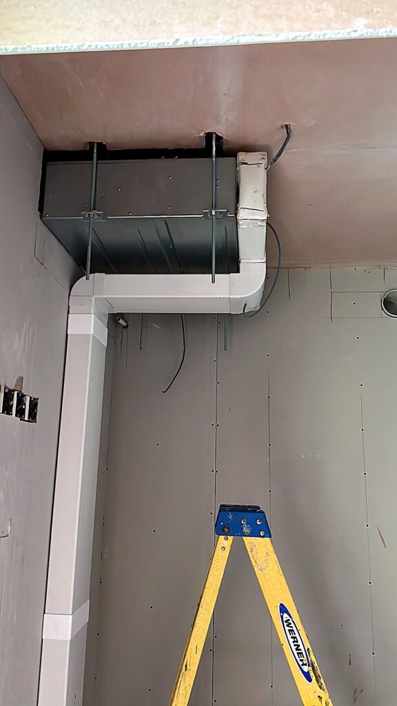 Ducted air conditioning unit installed above a ceiling