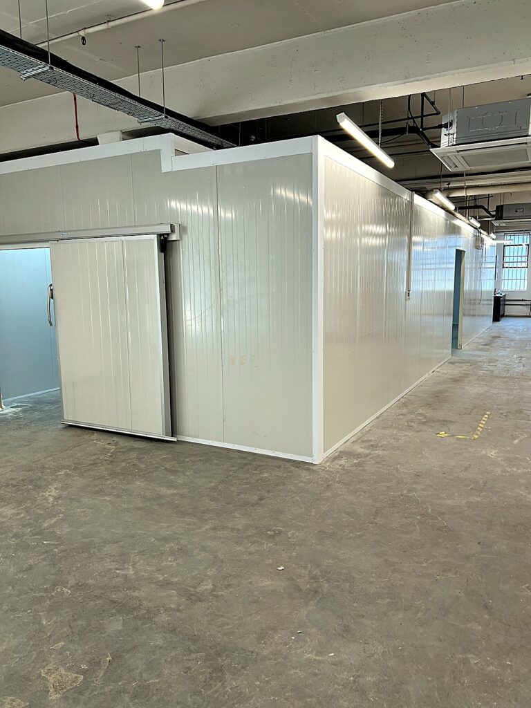Long walk-in cold room with sliding door in a warehouse