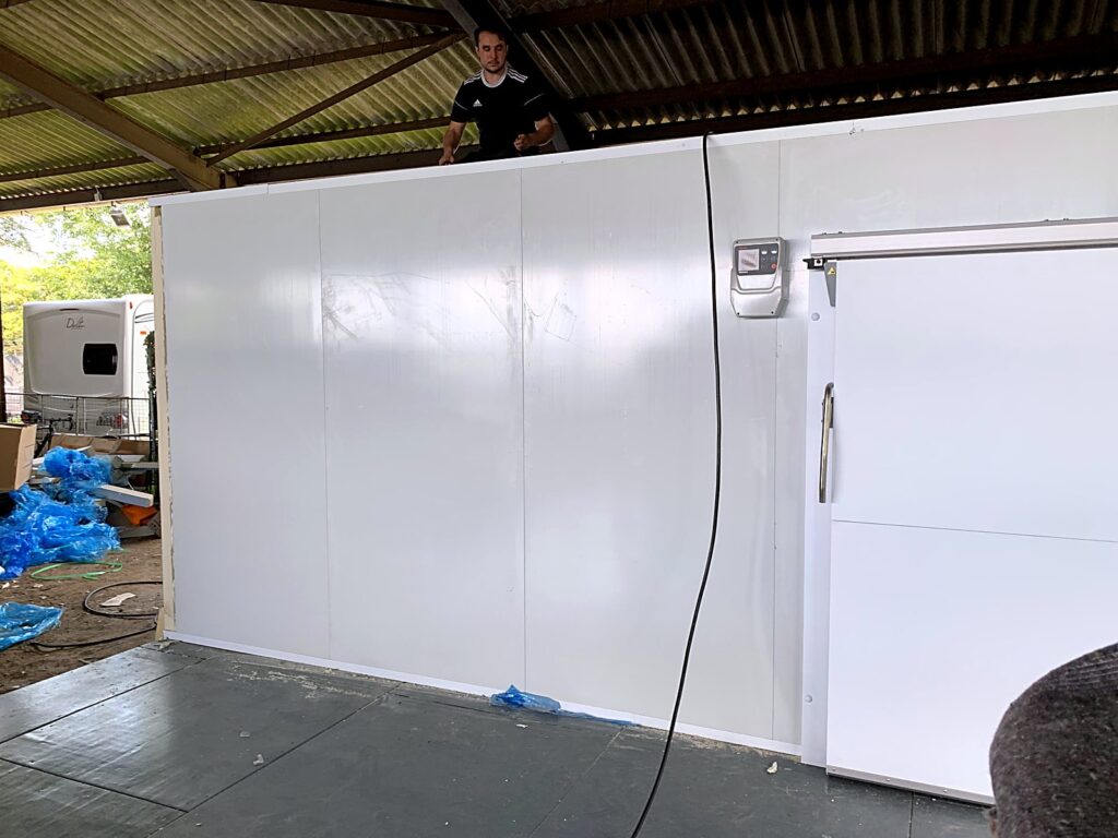 Engineer fitting the ceiling panels of a cold room with sliding door