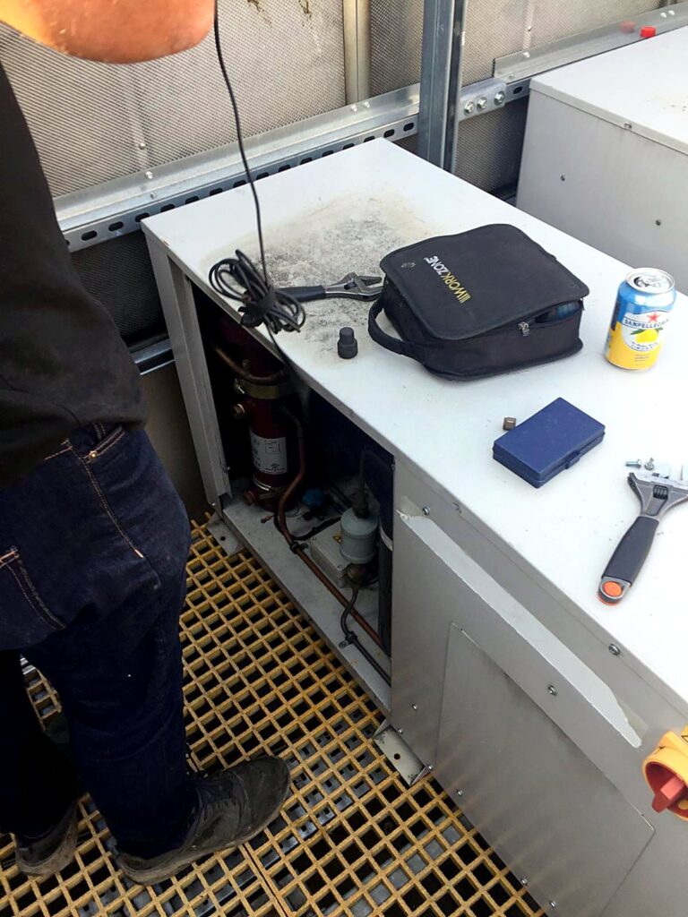 Engineer servicing a condensing unit with diagnostic tools